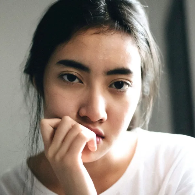 Jeune femme se rongeant un ongle, le regard soucieux