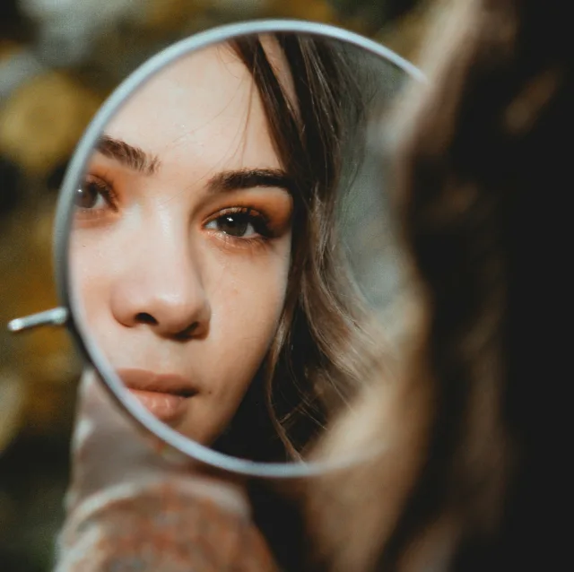 Reflection of a face in a small round mirror, searching gaze
