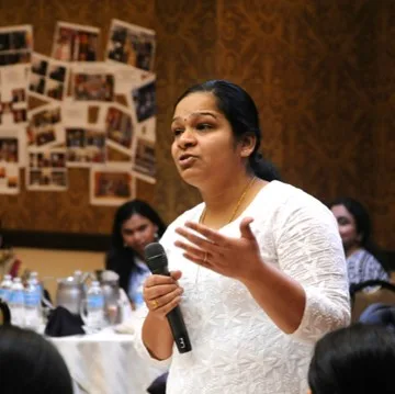 Woman speaking confidently into a microphone in front of an audience