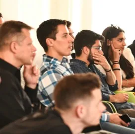 Attentive audience in a hall, one thoughtful listener in the foreground