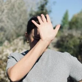 Person hiding their face behind their hand