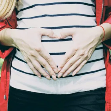 Pregnant woman forming a heart with her hands on her belly